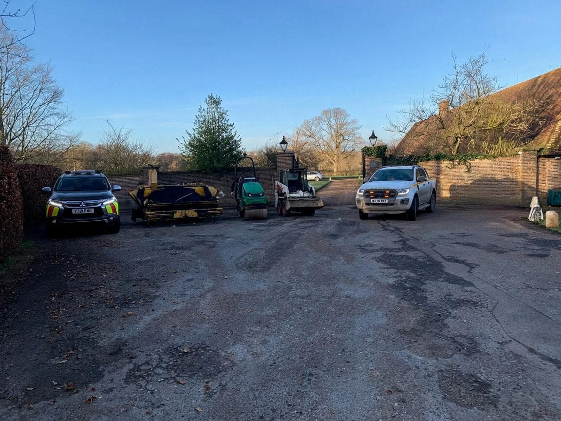 Victory Surfacing's pickups, road roller, skid-steer loader and paving plant lined up in a walled yard on a clear winter morning.