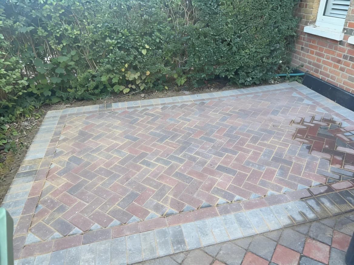 A newly laid herringbone block-paved patio with a contrasting soldier-course border, against a red-brick house.