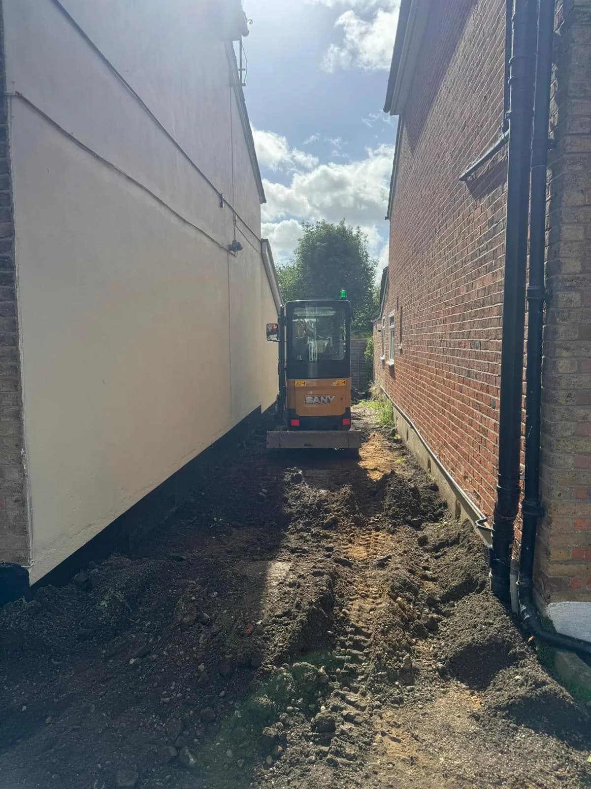 The worn gravel and bare-ground side access before the works