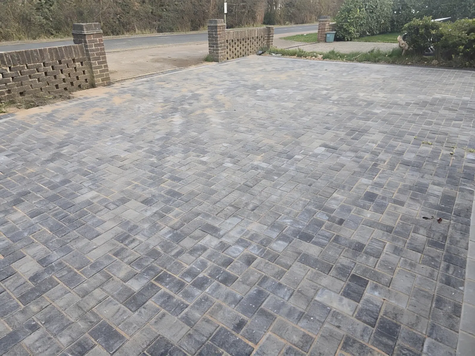 Finished charcoal block paving driveway with a contrasting soldier-course border outside a brick Surrey home