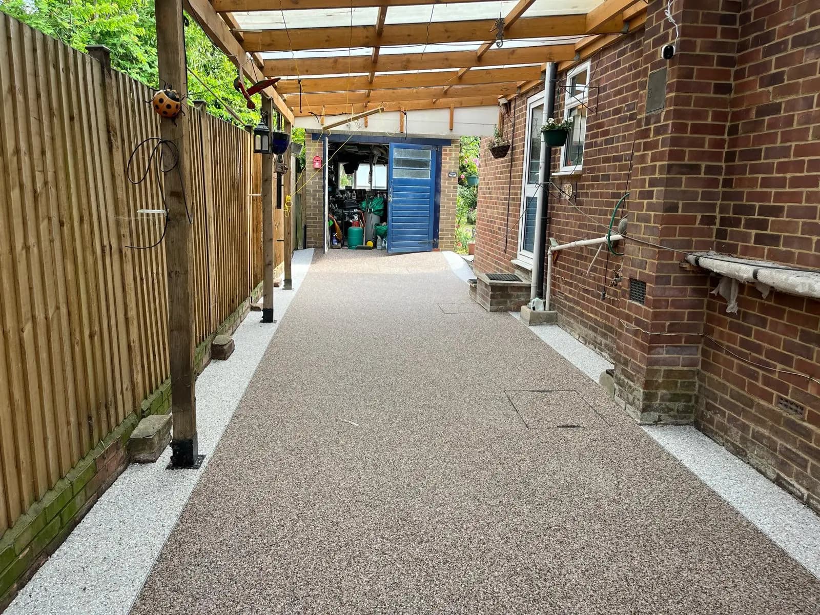 Finished silver-grey resin-bound side path under a lean-to in Crowthorne