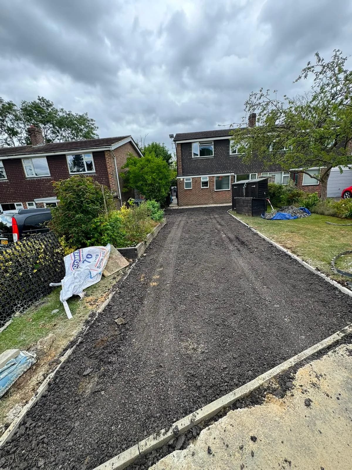 A surfacing crew laying and raking out fresh tarmac on a driveway